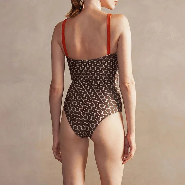 Women's dot-pattern one-piece swimsuit with matching wrap skirt set on a hanger.