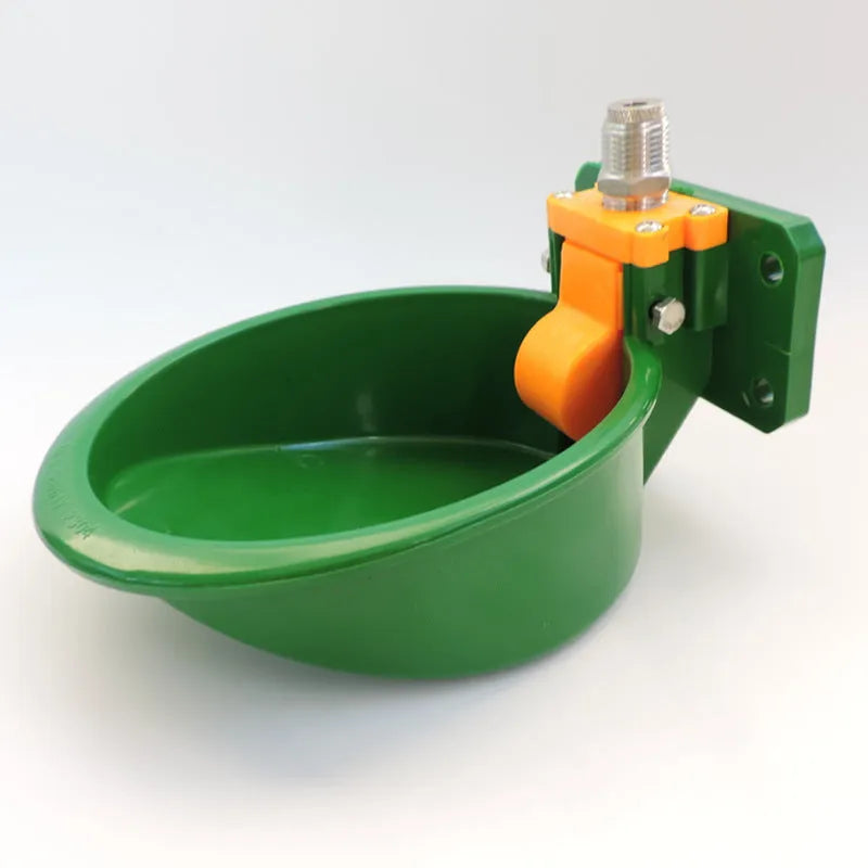 Green plastic automatic drinking bowl with nozzle for sheep and pigs on a farm.