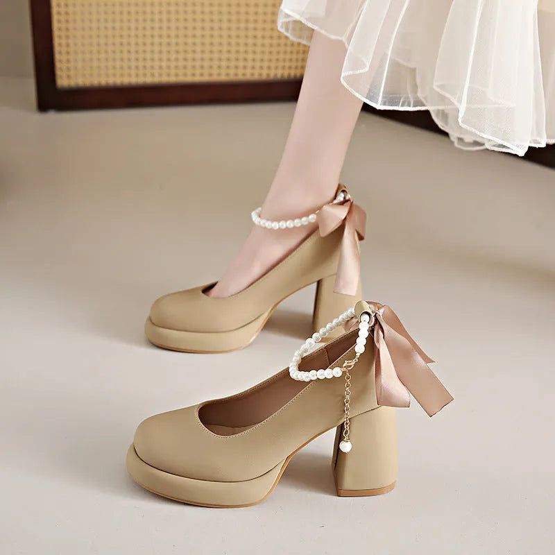Women's beige Mary Jane shoes with chunky heel and ankle strap buckle on a wooden floor.