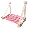 Pink wooden cat hammock bed with suction cups attached to a window, showing a cat lying on the linen mat.