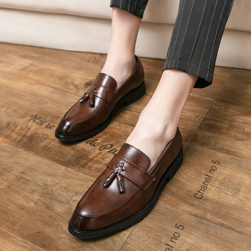 Men's black slip-on business casual shoes with a tassel detail and pointed toe.