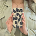 Black silicone iPhone case with a tulip flower design on the back.