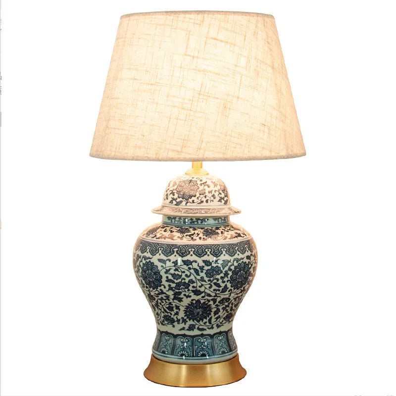 Chinese style blue and white porcelain table lamp with handmade ceramic base and cloth shade on bedside table
