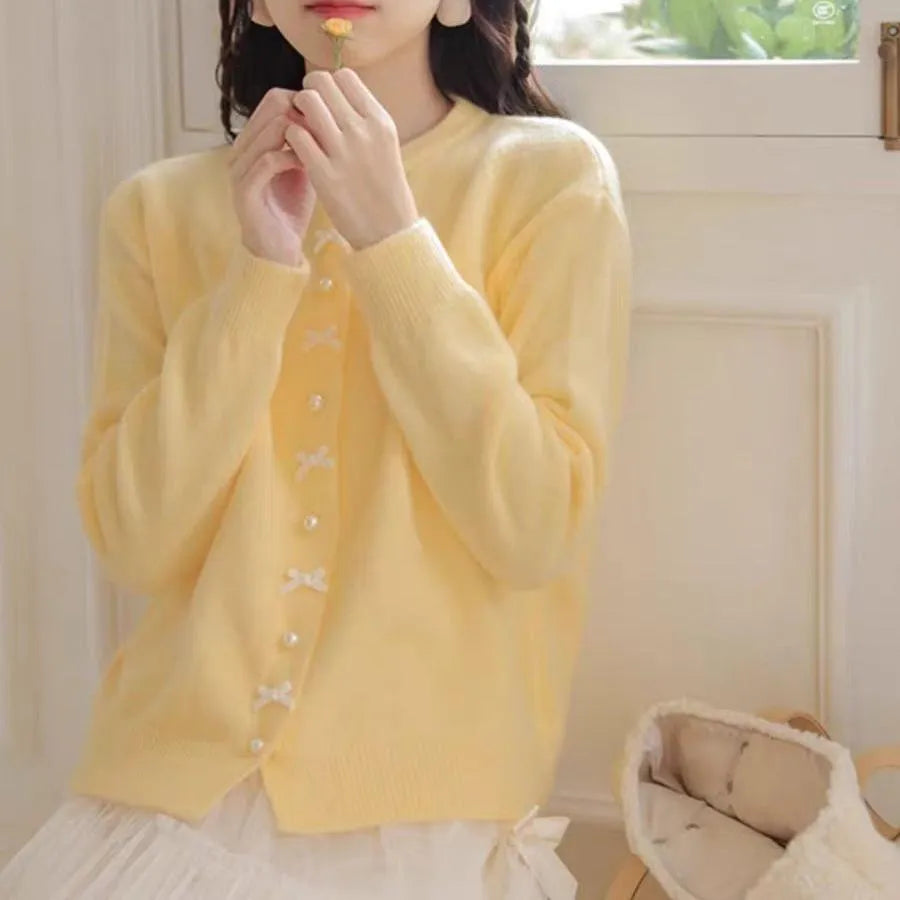 Women's solid colour cardigan with a bow and pearl buttons, shown in a light colour.