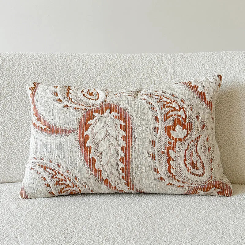 Amber jacquard paisley pillow cover on a sofa, showing textured fabric and botanical pattern.