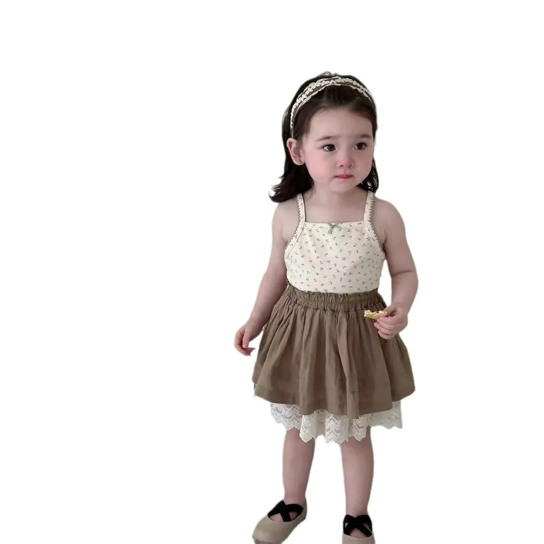Baby girl wearing floral camisole vest and brown cotton skirt with dots pattern on a white background