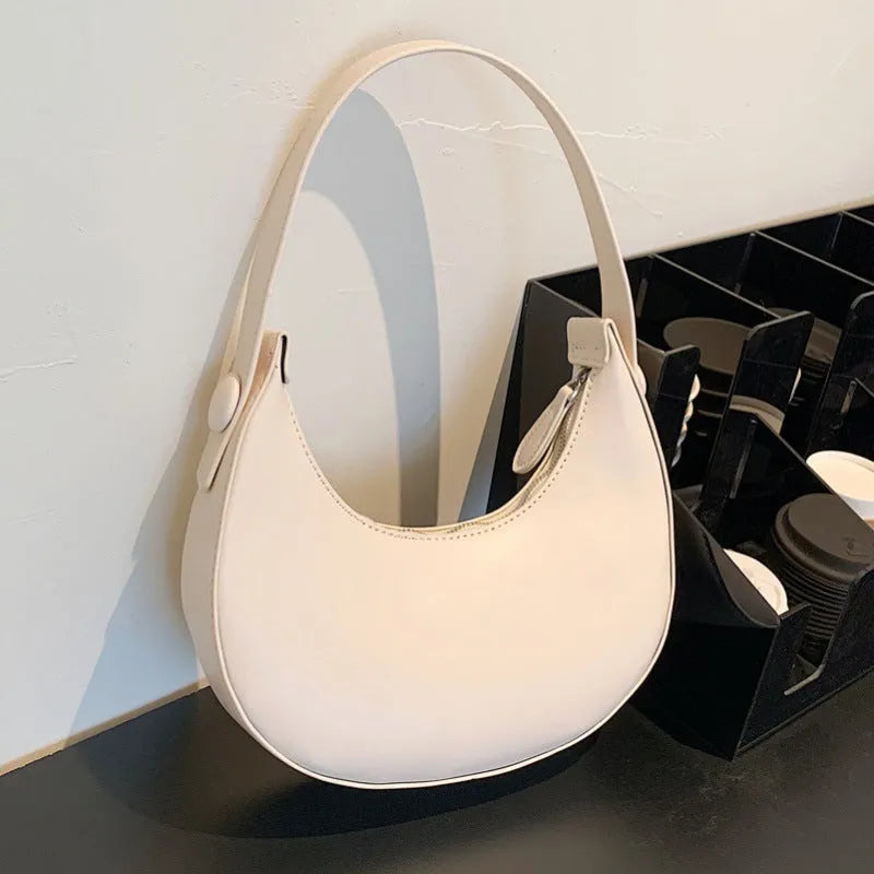 Women's retro-style PU shoulder bag in a dumpling shape, shown in cream yellow colour with a shoulder strap.