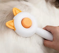 Circular greenish white pet grooming brush with stainless steel teeth and rubber massage nodules.