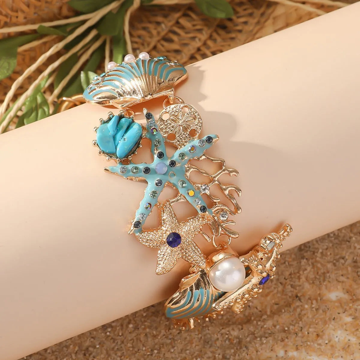 Starfish-shaped alloy bracelet with rhinestone anchor and shell details in turquoise, red, or blue.