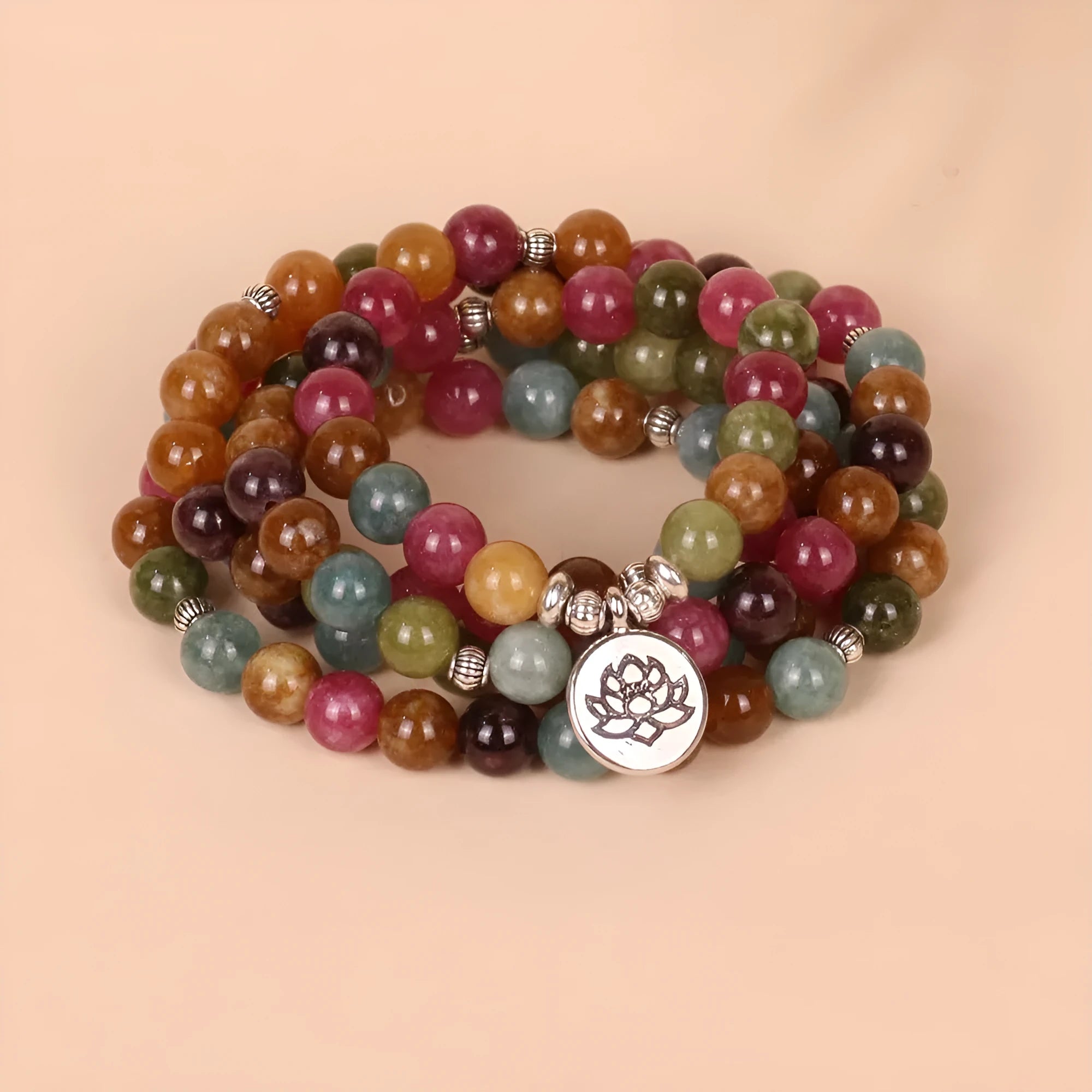 Multi-layer beaded bracelet with 108 tourmaline beads, lotus charm, and alloy clasp on a wrist.