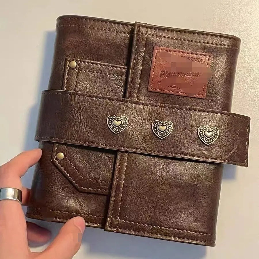 Brown A7 leather buckle notebook with loose-leaf binding on wooden surface