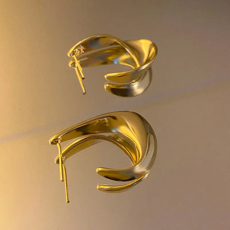 Metal twisted geometric hoop earrings with electroplated gold or silver finish showing round wire design