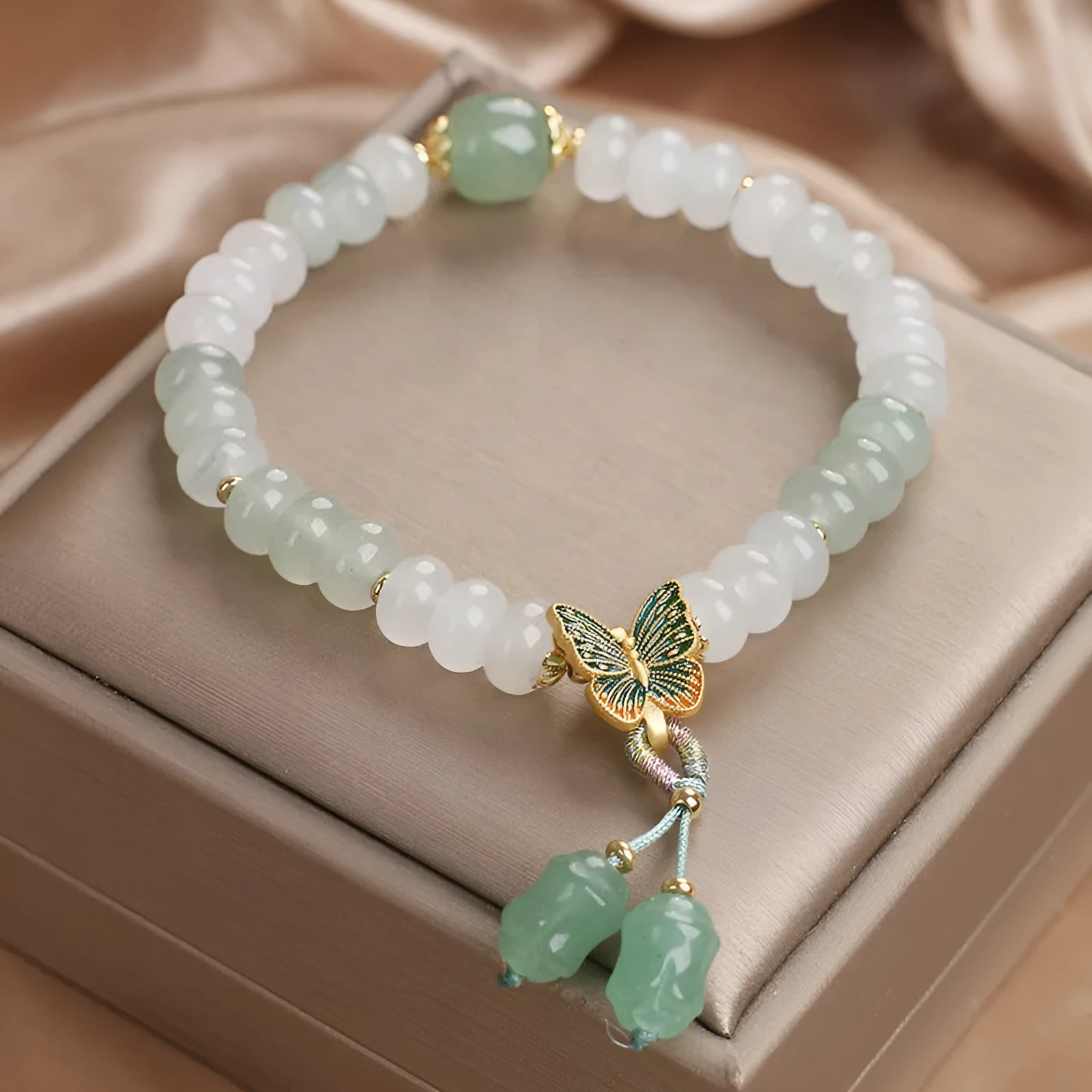 Green crystal women's bracelet with abacus beads, a butterfly tassel, pearls, and rhinestones.