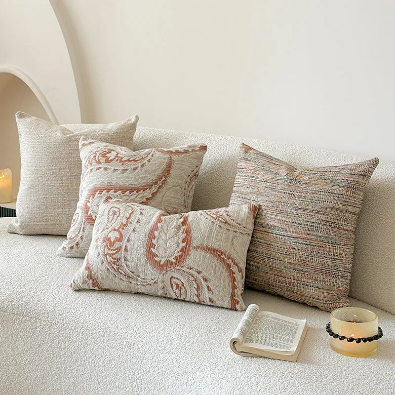 Amber jacquard paisley pillow cover on a sofa, showing textured fabric and botanical pattern.