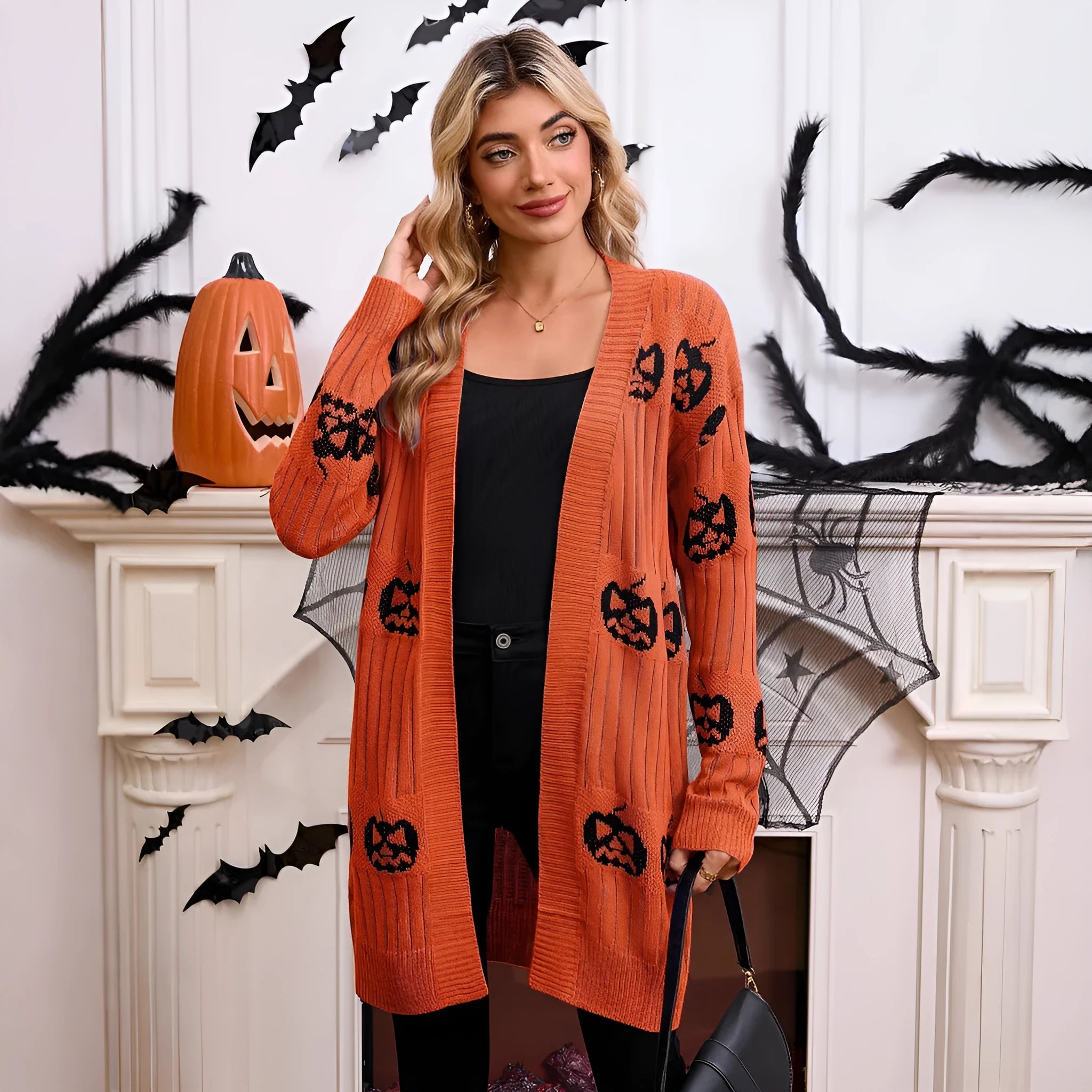 Women's black Halloween cardigan with orange pumpkin head jacquard knit pattern, shown open.