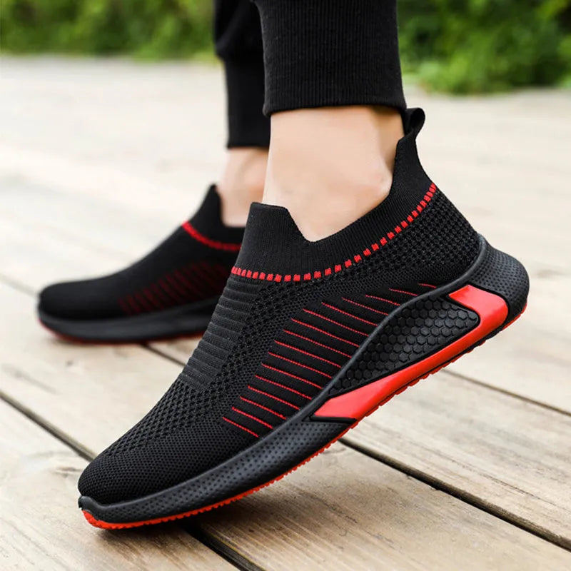 Men's black and white mesh slip-on sneakers with striped design and flat sole.