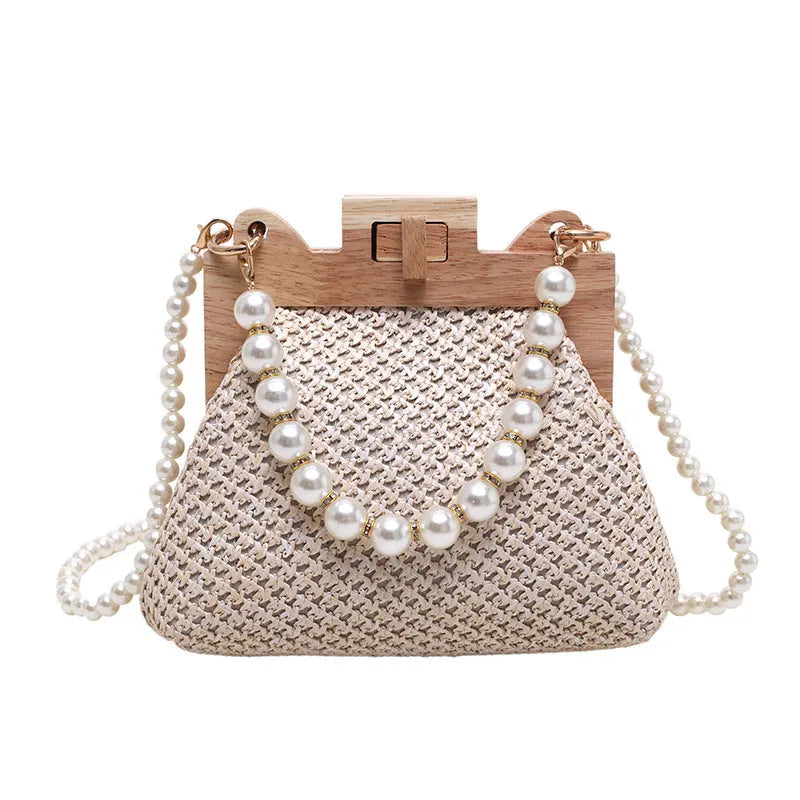 Women's woven straw shoulder bag with pearl chain strap in beige, showing its horizontal square shape.