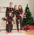 Matching red plaid and cartoon print Christmas pyjamas set for adults, children and a dog on a festive background.