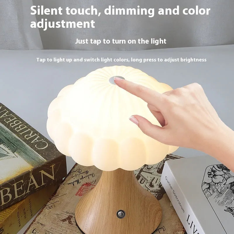 Mushroom-shaped touch control night light in cream colour on a wooden table.