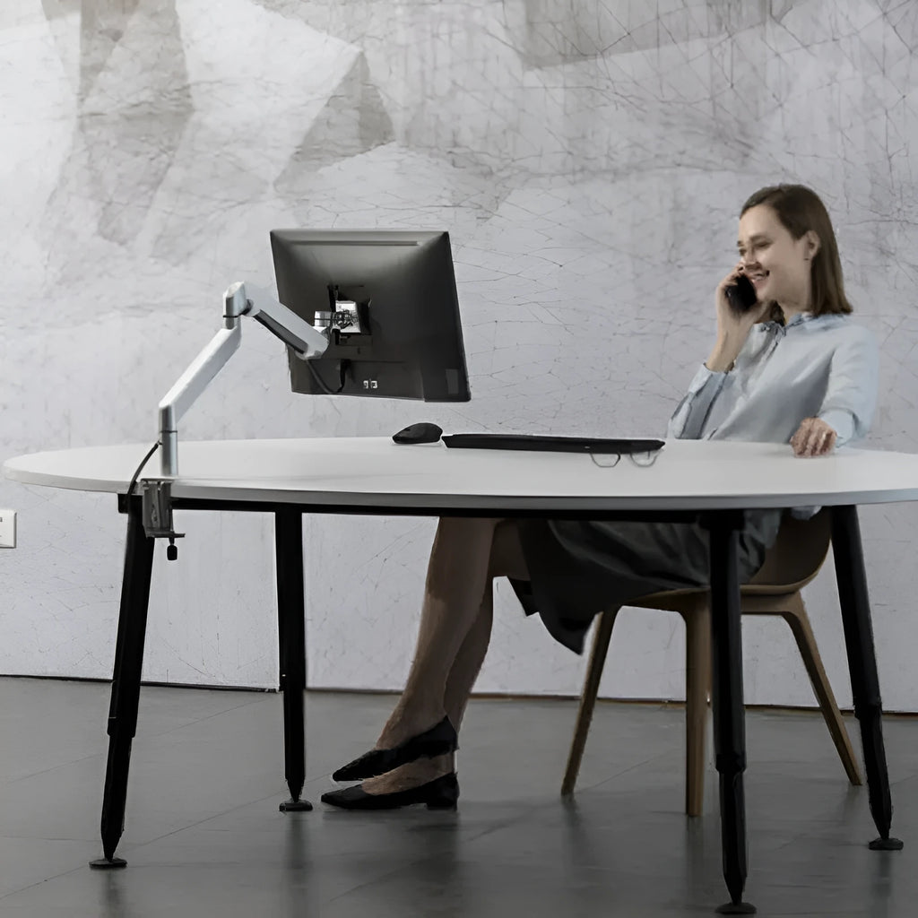 Silver aluminium hover arm laptop stand with adjustable height mechanism on wooden desk