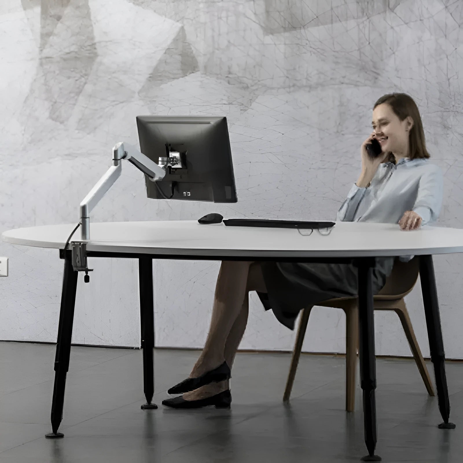 Silver aluminium hover arm laptop stand with adjustable height mechanism on wooden desk