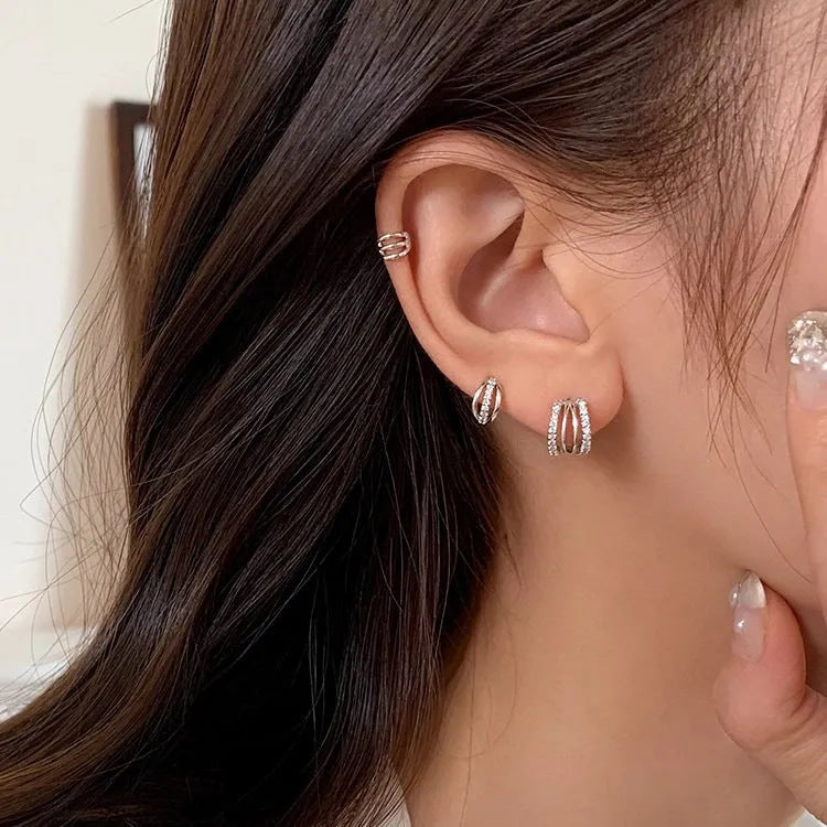 A pair of geometric-designed 925 sterling silver earrings with needle posts on a plain background.
