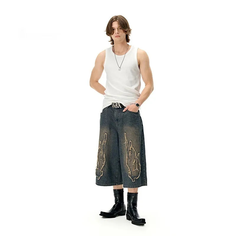 Men's black denim shorts with a cropped flame embroidery patch on the leg