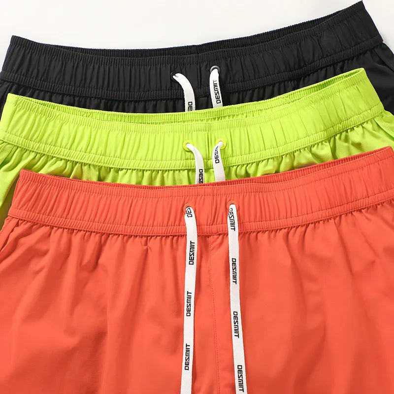 Men's loose orange polyester beach shorts on a hanger against a neutral background