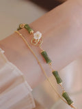 Handmade natural olivine bracelet with double layer design and Bells of Ireland charms on a wrist.