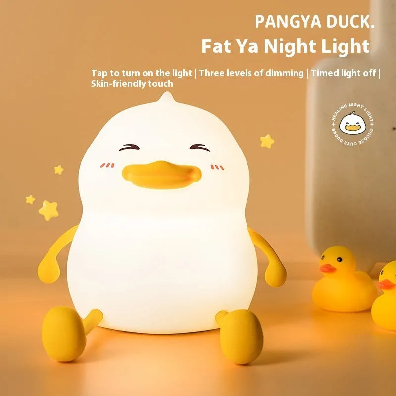 Chubby silicone and plastic night light on desk holding a mobile phone with soft LED glow.