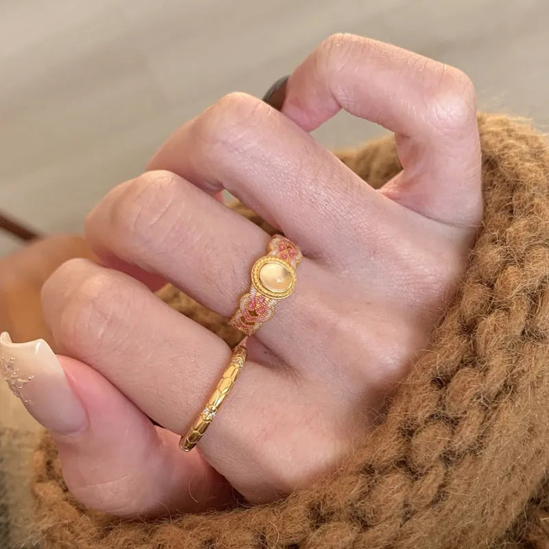 Geometric open ring for women with pink crystal enamel decoration on a gold-toned band.