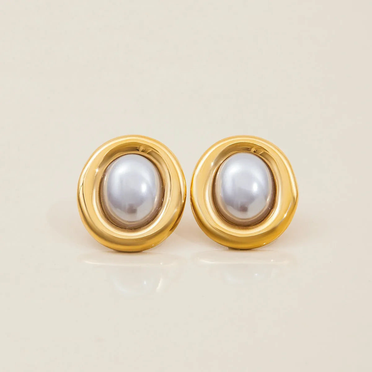 A pair of stainless steel post ear studs with small vintage-style pearl accents on a silver-tone background.