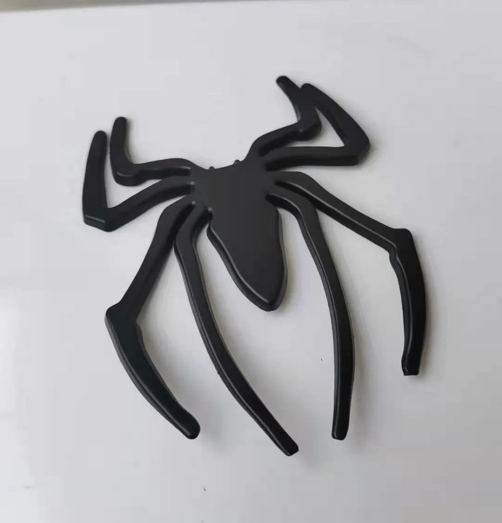 Three-dimensional metal spider car bumper sticker in zinc alloy, shown in gold colour.
