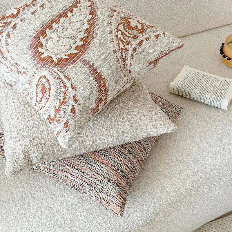 Amber jacquard paisley pillow cover on a sofa, showing textured fabric and botanical pattern.