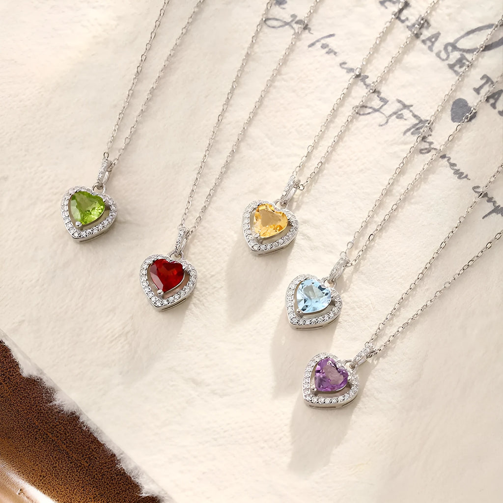 Heart-shaped sterling silver necklace with a round amethyst gemstone on a cross chain.