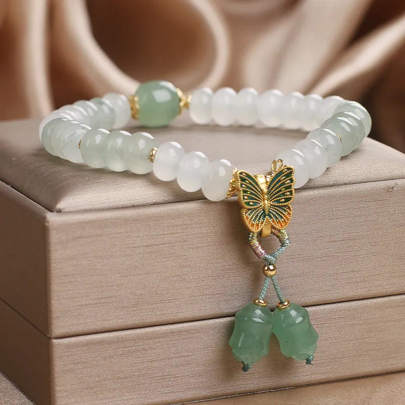 Green crystal women's bracelet with abacus beads, a butterfly tassel, pearls, and rhinestones.