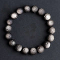 Natural obsidian crater ball bracelet showing polished spherical beads in silver stone meteorite colour with visible mineral texture