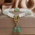 Green crystal women's bracelet with abacus beads, a butterfly tassel, pearls, and rhinestones.