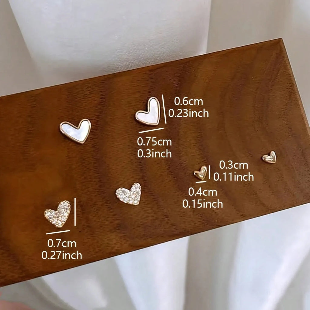 Three pairs of heart-shaped earrings in gold, black, pink, and black white colours with love-themed girly styling