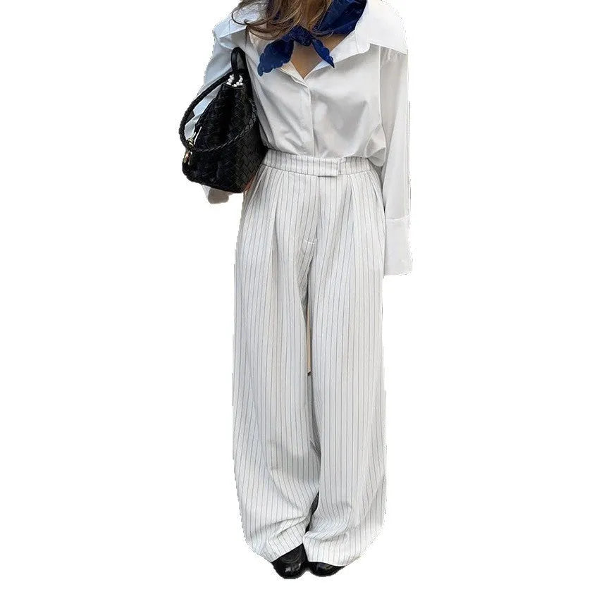 White striped wide-leg women's trousers with side zip, laid flat to show loose fit and pattern.