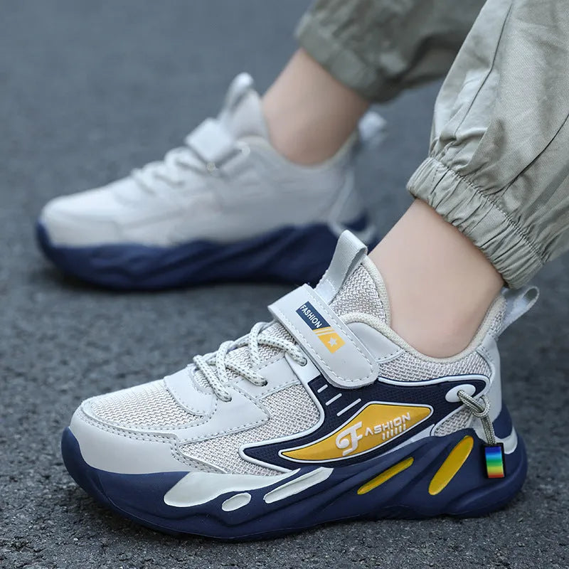 Boys' blue and black platform sports running shoes with Velcro strap on a hard ground surface.