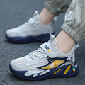 Boys' blue and black platform sports running shoes with Velcro strap on a hard ground surface.