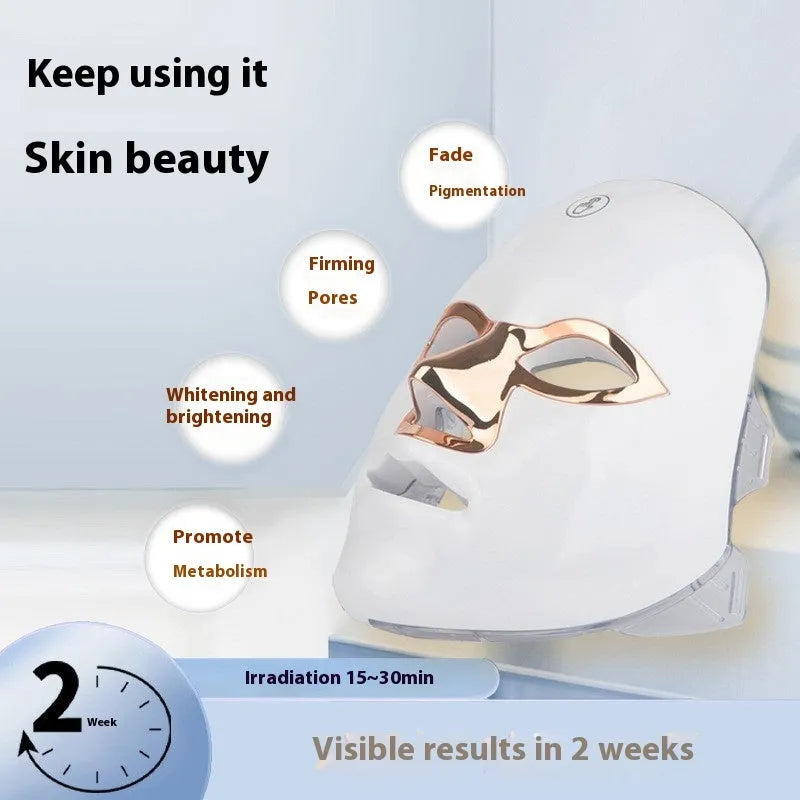Rechargeable manual touch LED beauty mask in white with gold rim, showing charging cable and strap.
