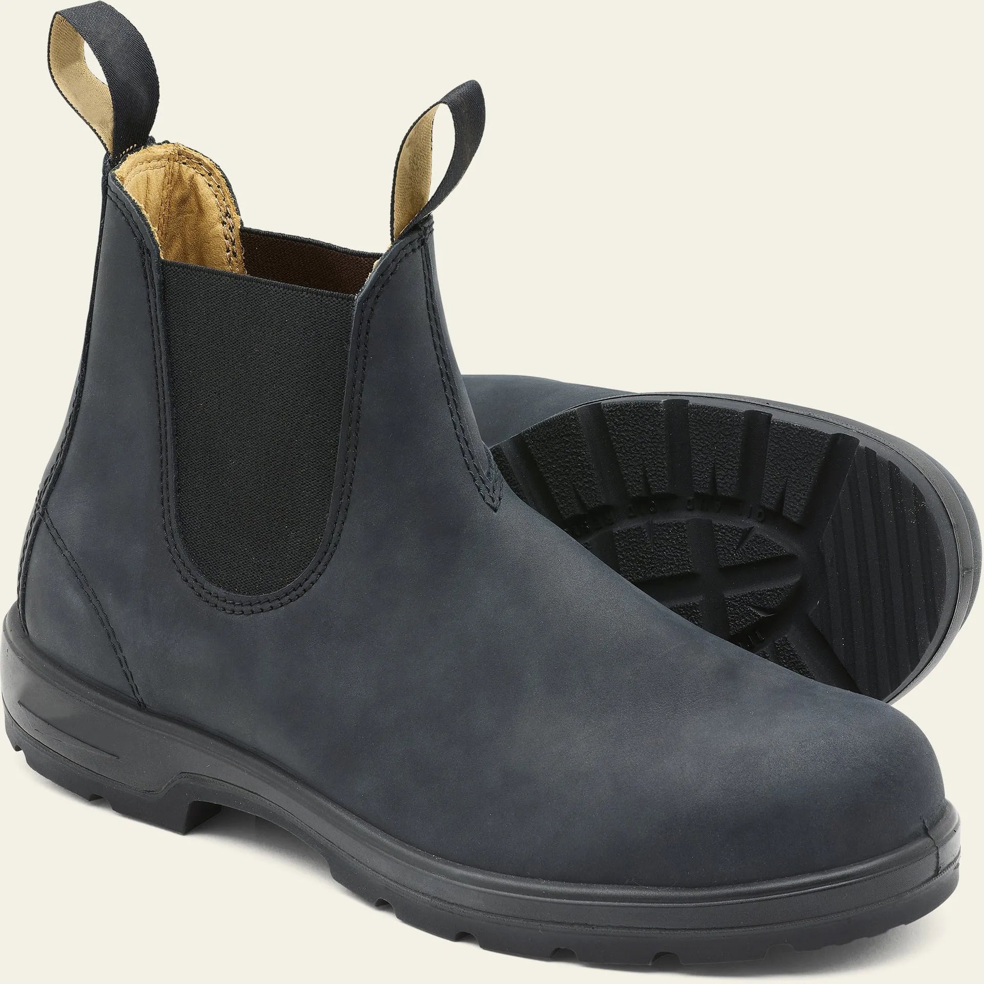 Vintage brown Chelsea boots with frosted finish and car suture detailing on a wooden floor.