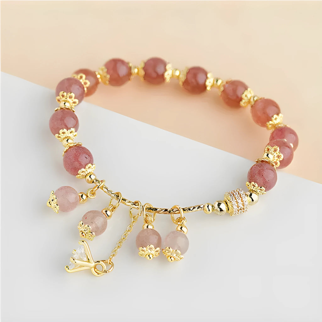 Pink heart-shaped strawberry quartz and pearl women's bracelet on a wrist.