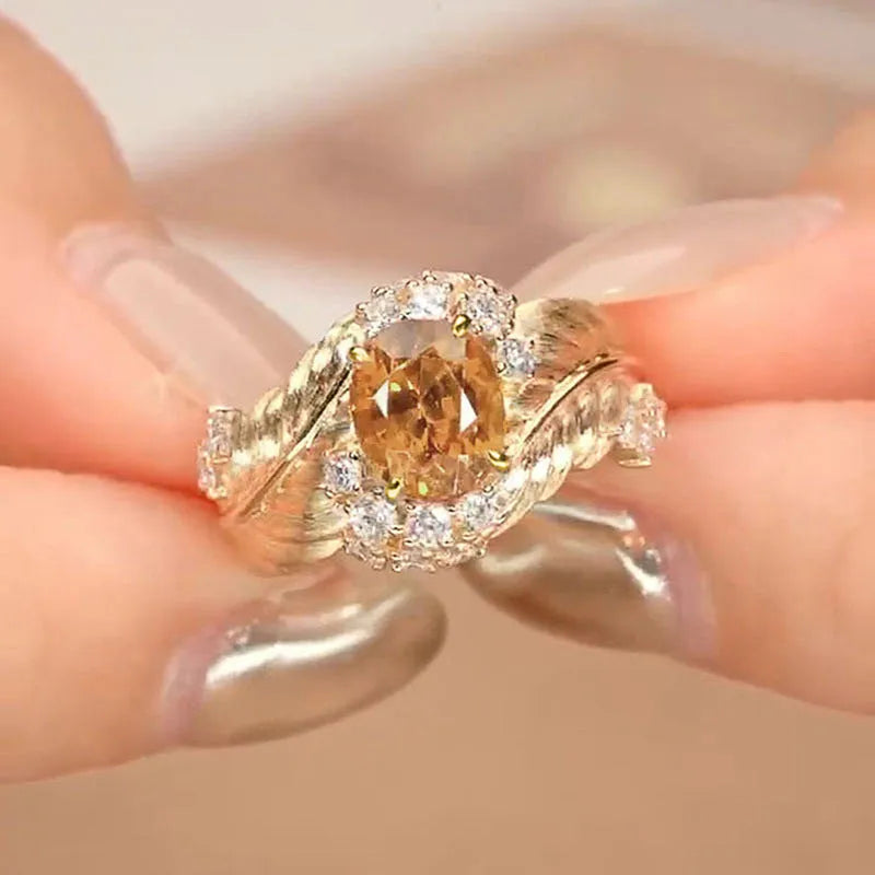 Gold-coloured women's ring with embossed feather pattern and yellow zircon stone inlay on copper base