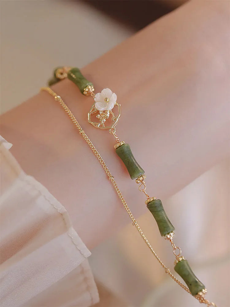 Handmade natural olivine bracelet with double layer design and Bells of Ireland charms on a wrist.