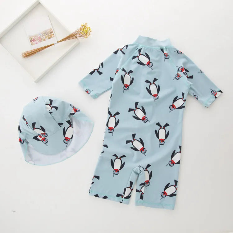 Boy's blue penguin print long sleeve swimsuit top and shorts with matching swimming cap.