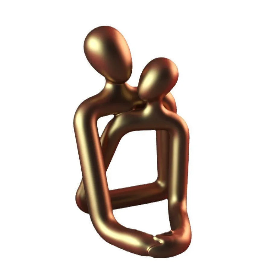 Modern loving couple resin statue in gold or milky white finish on a wooden desk.